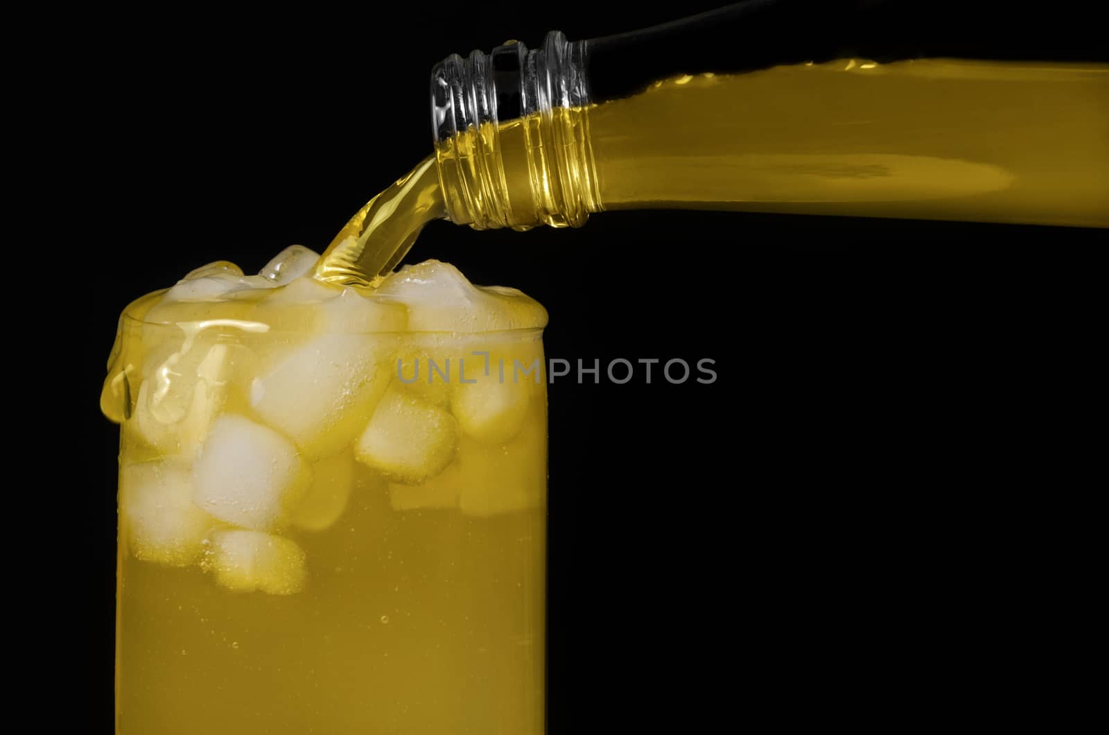 Lemonade is poured into the glass, on a black background by Gaina