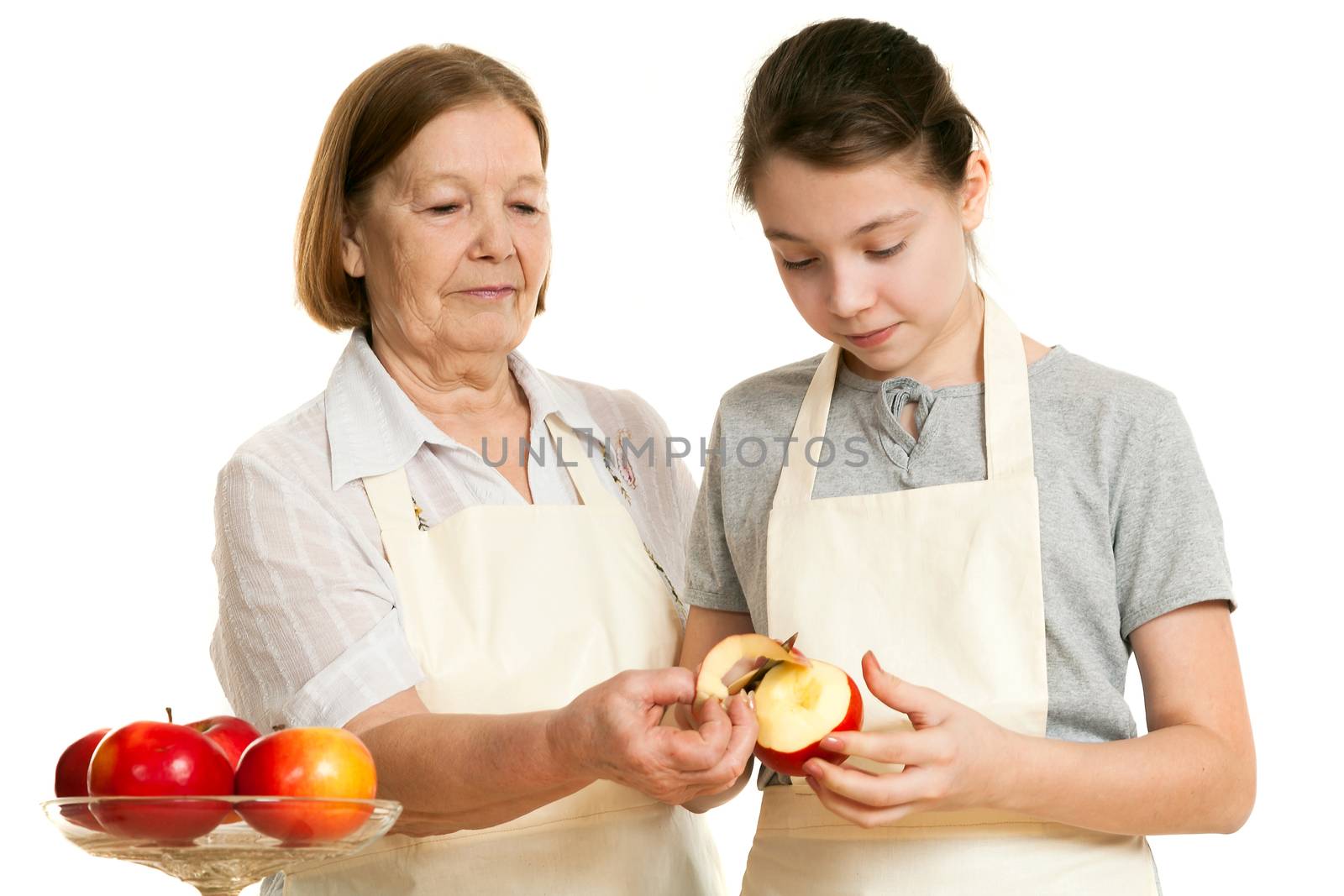 the grandmother teaches the granddaughter to cut off a peel from apple on a white background