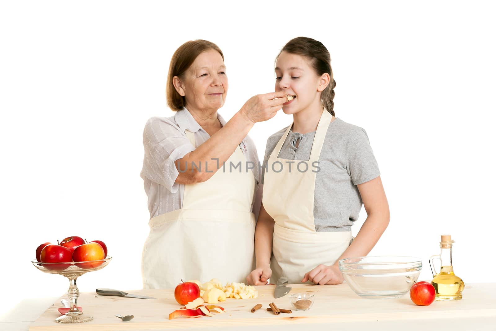 the grandmother and the granddaughter treat each other with apple pieces on a white background