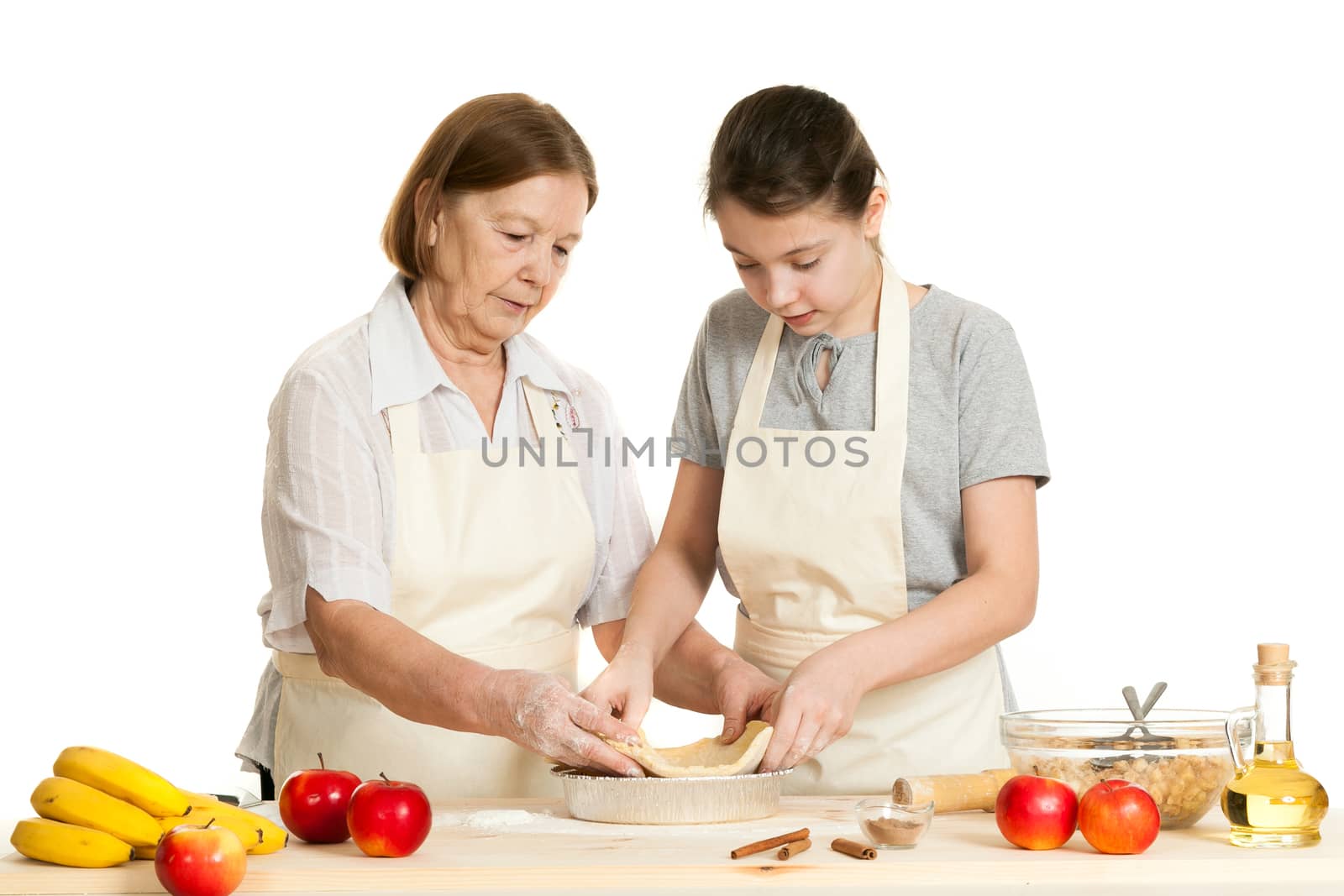 the grandmother and the granddaughter stack dough in a form for pie