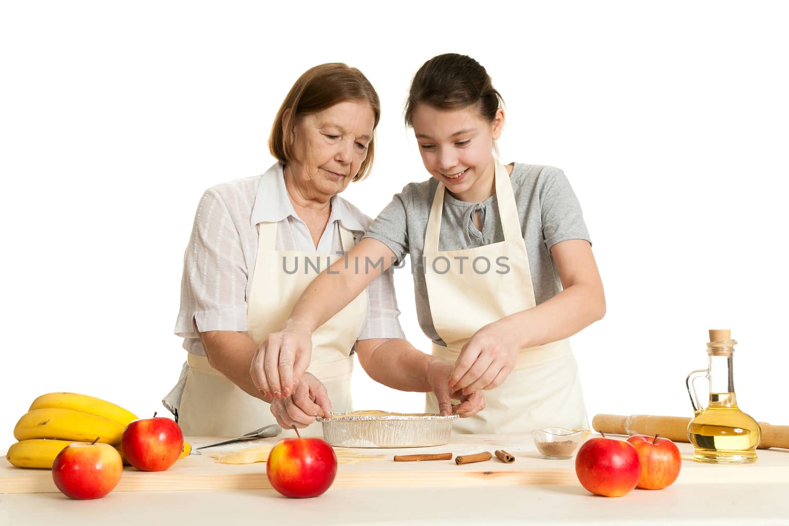 the grandmother and the granddaughter stack dough strips for ornament in a form for pie
