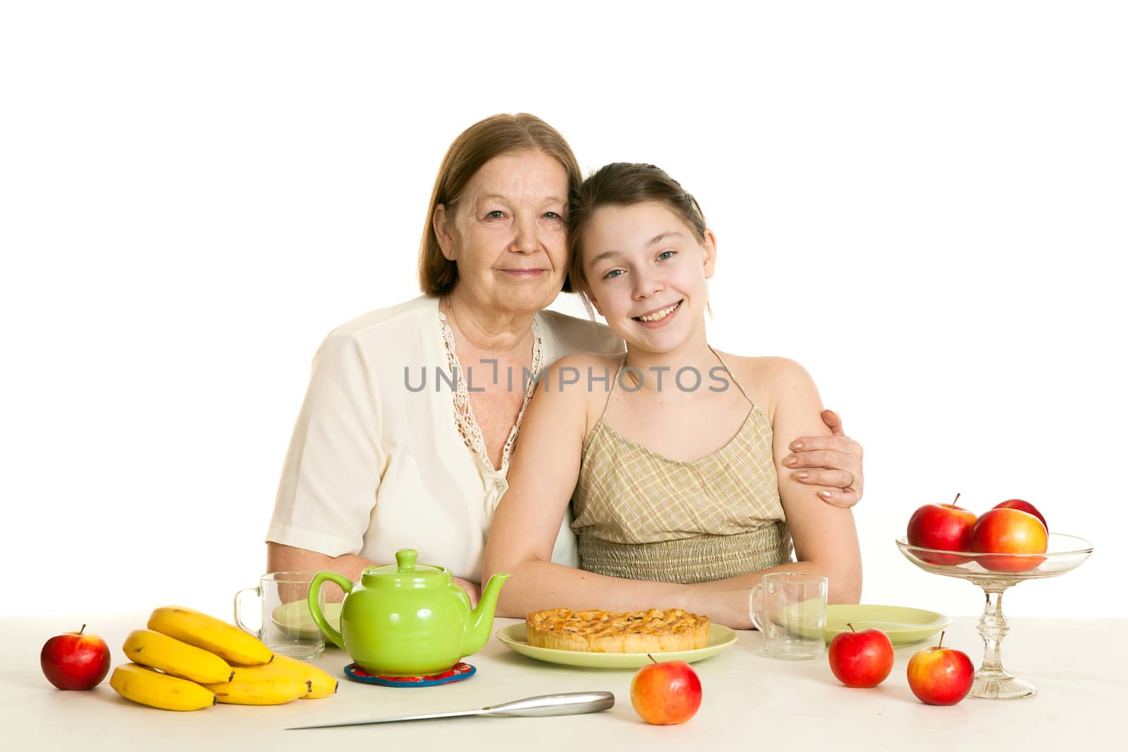 the grandmother and the granddaughter sit at a table with the made pie
