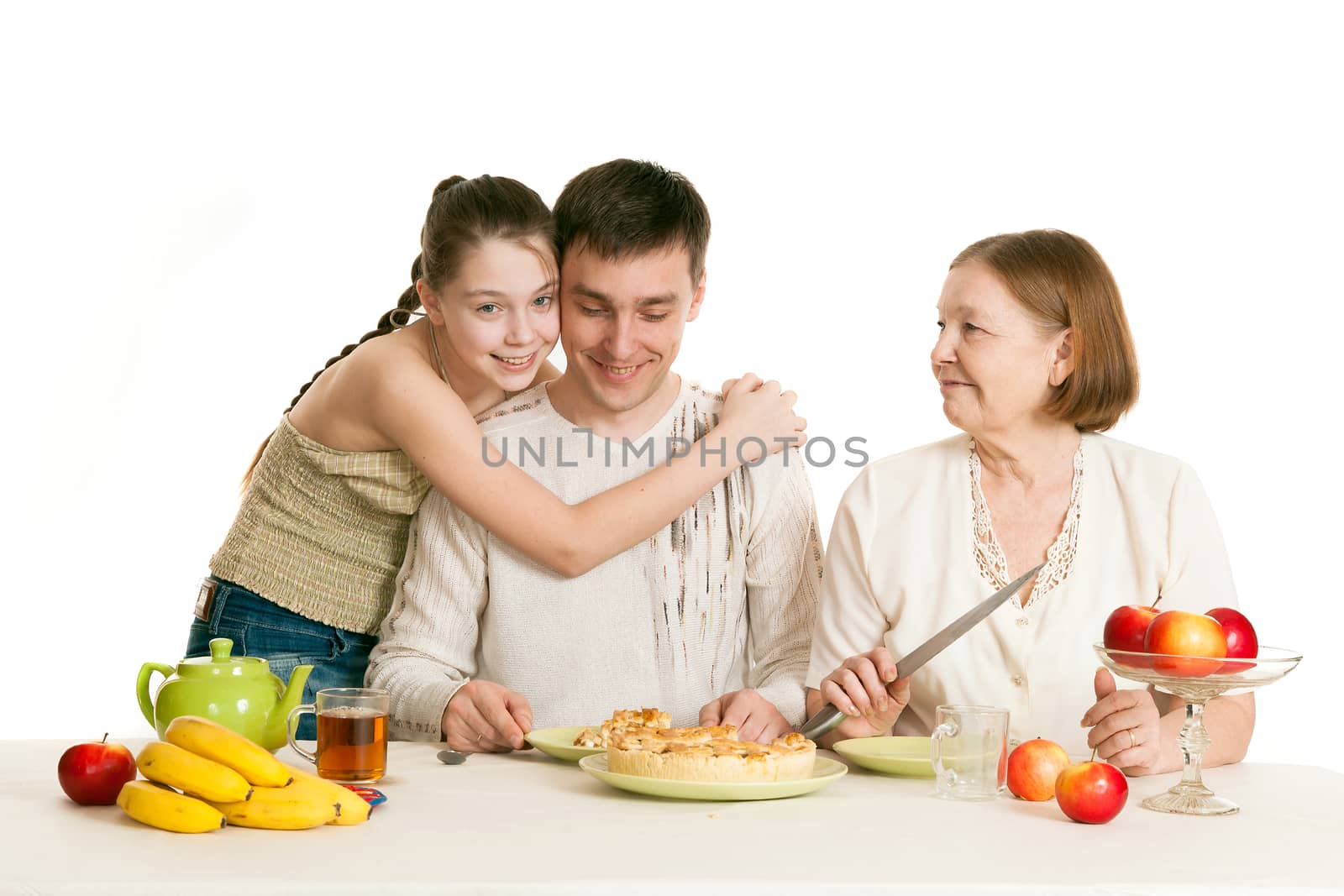 the grandmother and the granddaughter treat the father with pie and tea at a table