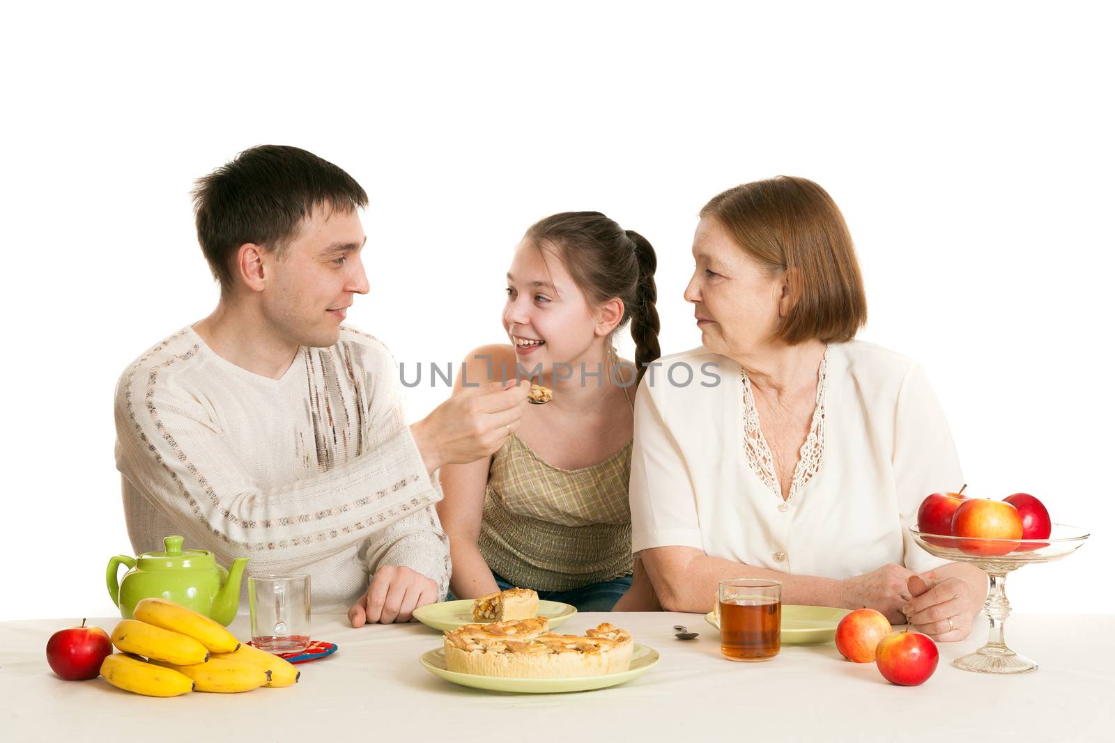 the grandmother and the granddaughter treat the father with pie and tea at a table