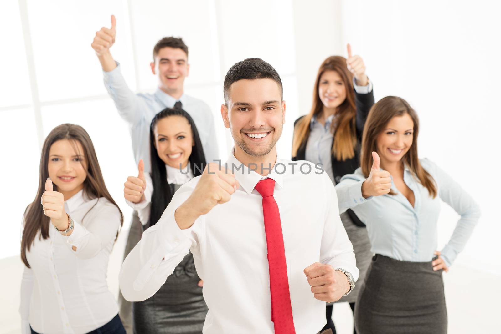 Successful arabian businessman standing proudly with his young business team. They showing thumbs up and looking at camera.