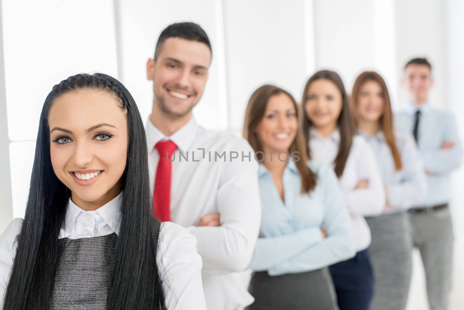 Successful young businesswoman standing proudly with her young business team and looking at the camera.