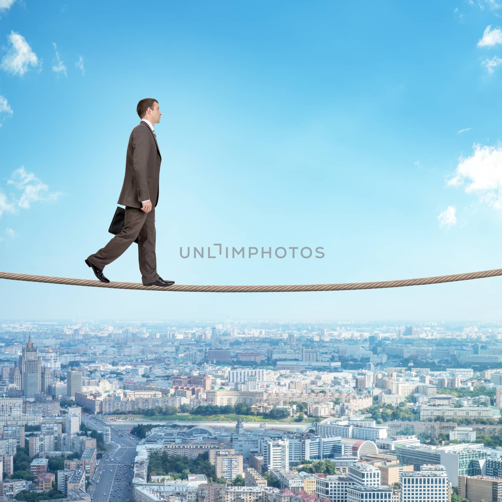 Businessman walking on rope on blue sky background