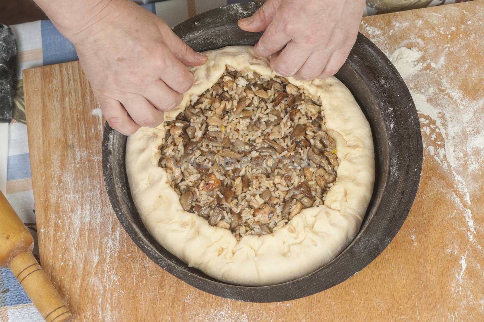 Making pie. Putting filling on raw dough in black metal baking form