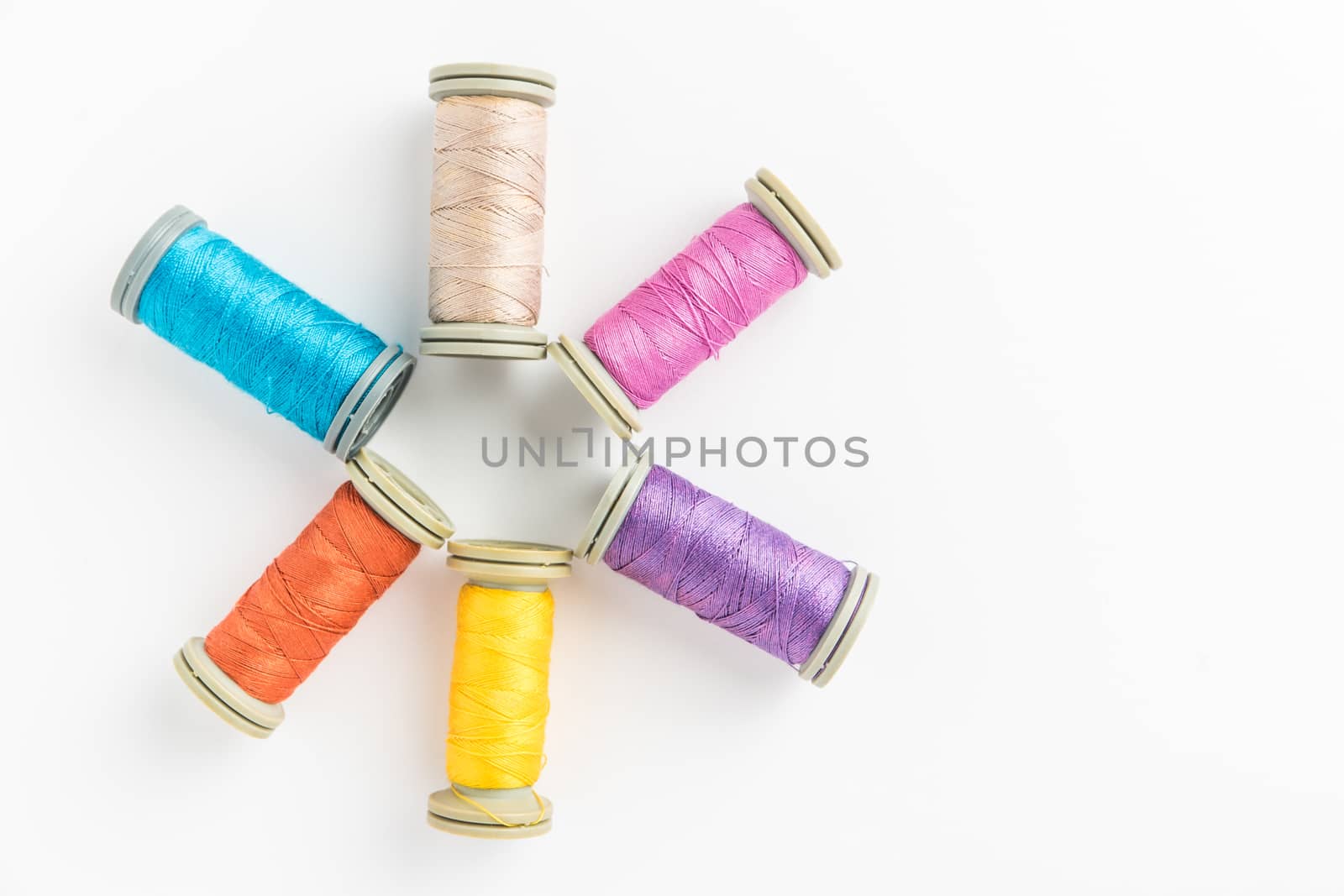 Multi-colored threads, sewing kit, a set of tailor on white background. Top view with copy space.
