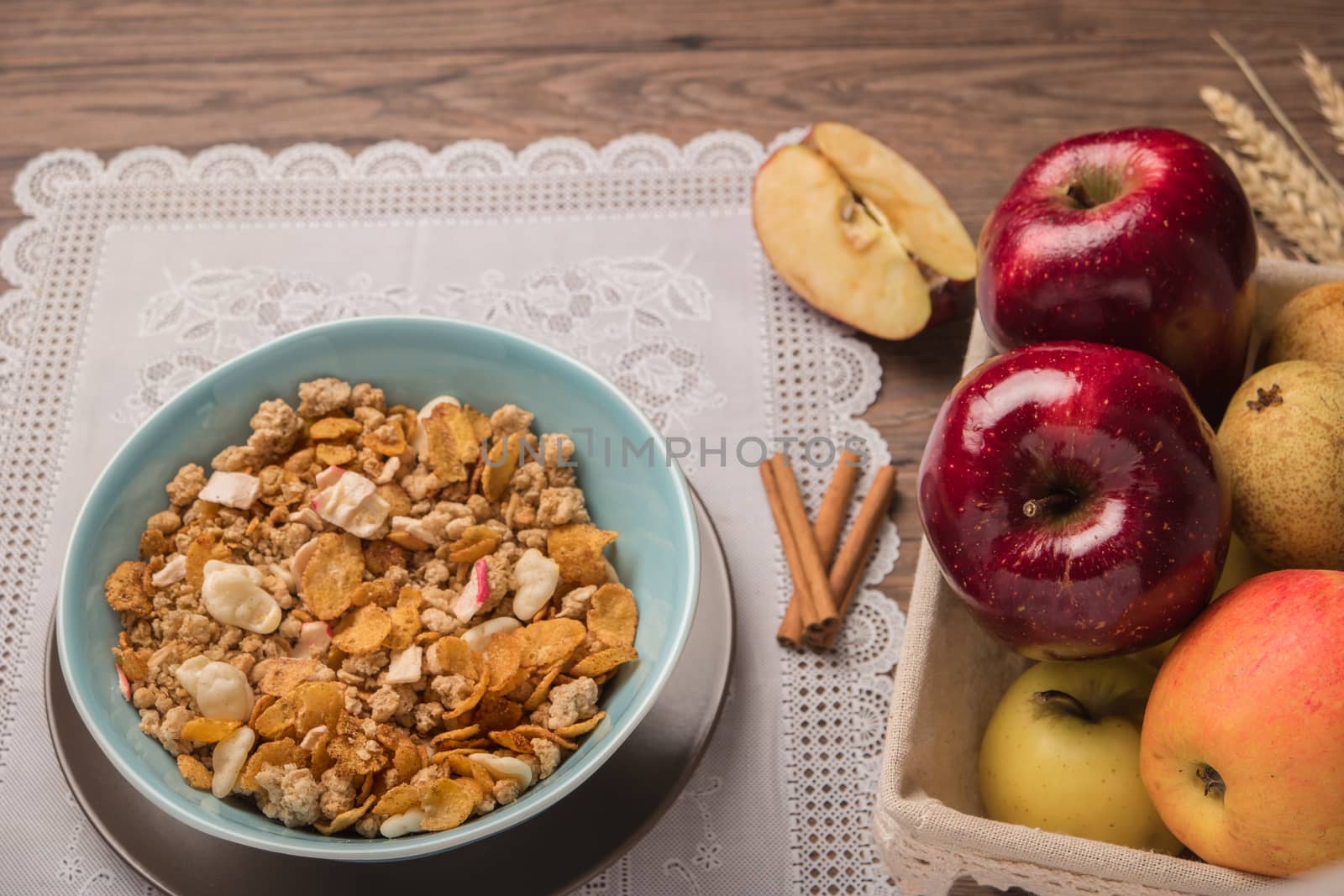 Healthy breakfast with muesli, red apple and cinnamon on rustic wood by AnaMarques
