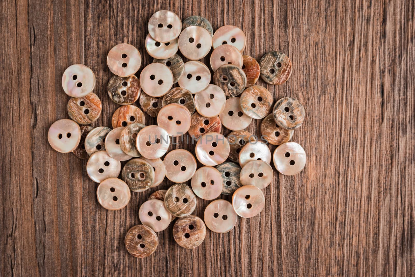 Set of different colored buttons over rustic wooden texture. by AnaMarques