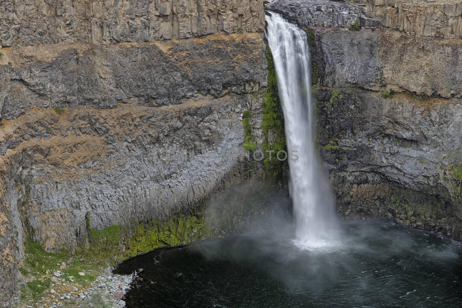 The canyon at the falls is 115 meters (377 feet) deep, exposing a large cross-section of the Columbia River Basalt Group. These falls and the canyon downstream are an important feature of the channeled scablands created by the great Missoula Floods that swept periodically across eastern Washington and across the Columbia River Plateau during the Pleistocene epoch. The ancestral Palouse river flowed through the currently dry Washtucna Coulee to the Columbia River. The Palouse Falls and surrounding canyons were created when the Missoula Floods overtopped the south valley wall of the ancestral Palouse River, diverting it to the current course to the Snake River by erosion of a new channel. The area is characterized by interconnected and hanging flood-created coulees, cataracts, plunge pools, kolk created potholes, rock benches, buttes and pinnacles typical of scablands. Palouse Falls State Park is located at the falls, protecting this part of the uniquely scenic area.
