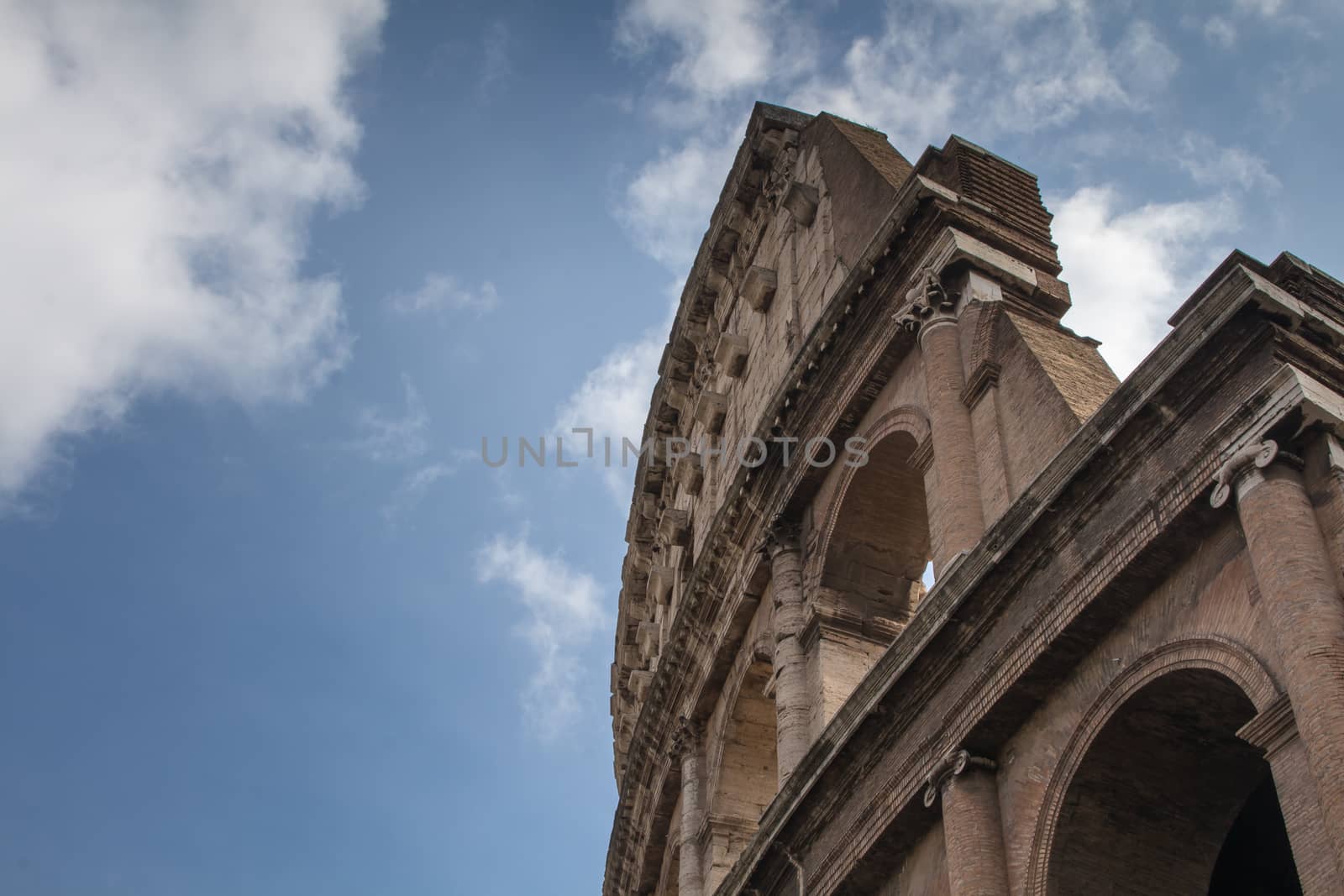 Although partially ruined because of damage caused by earthquakes and stone-robbers, the Colosseum is still an iconic symbol of Imperial Rome. Blue sky with clouds.