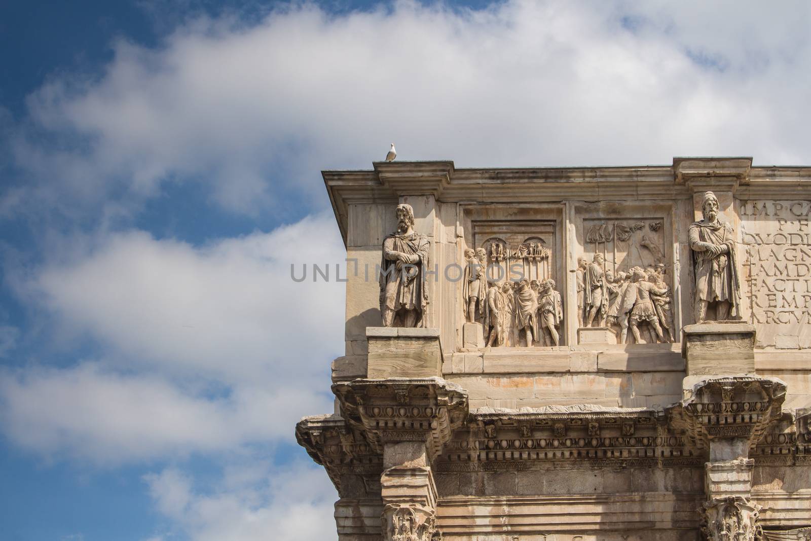 Details of the decorations of the Triumphal Arch beside Colosseum in Rome. Intense clouds on the blue sky.