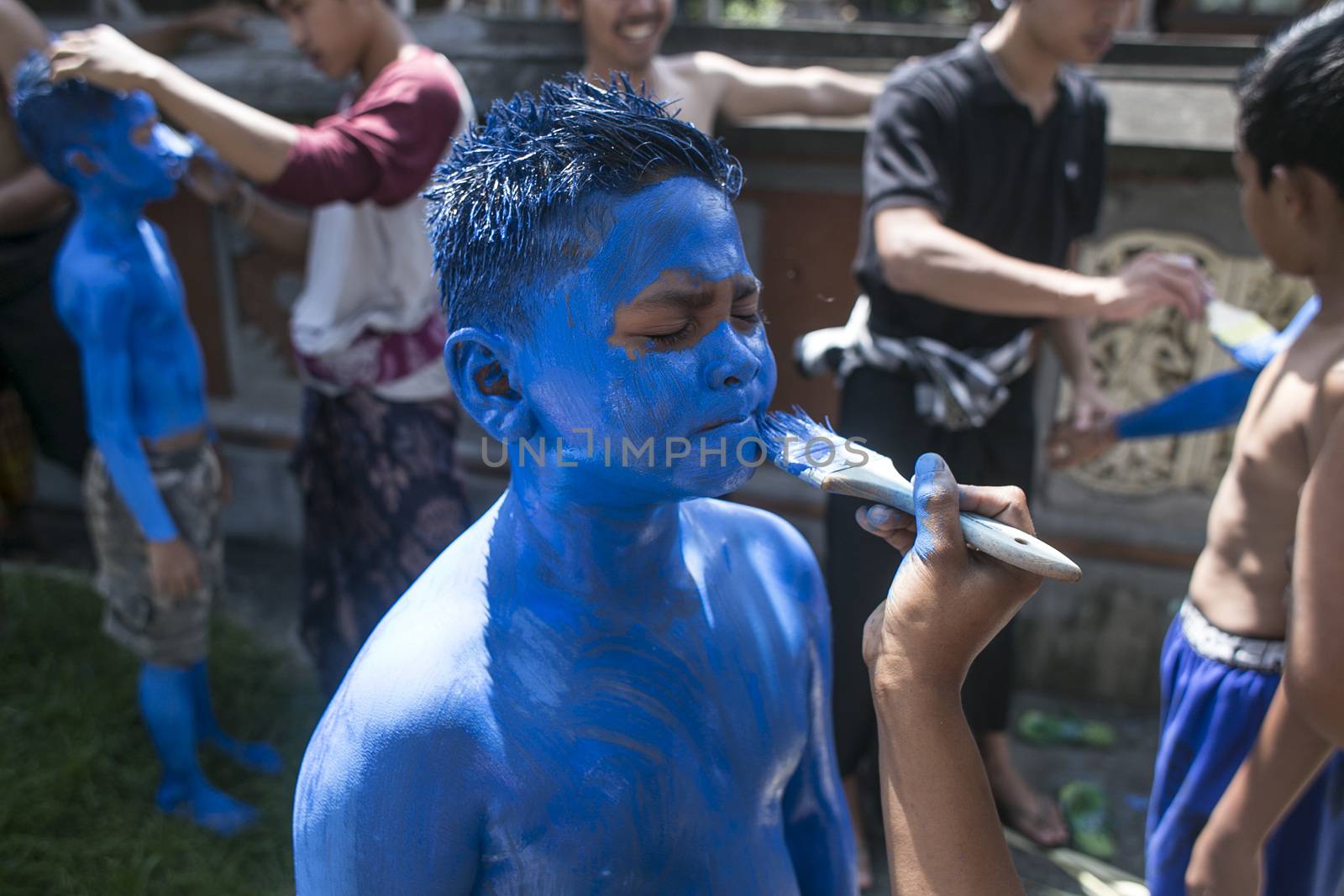 INDONESIA, Gianyar, Bali: A Balinese teenager is painted by one of his friends, during the Grebeg ritual, on March 16, 2016, in Tegallalang village, Gianyar, Bali, Indonesia. During the biannual ritual, young members of the community parade through the vi