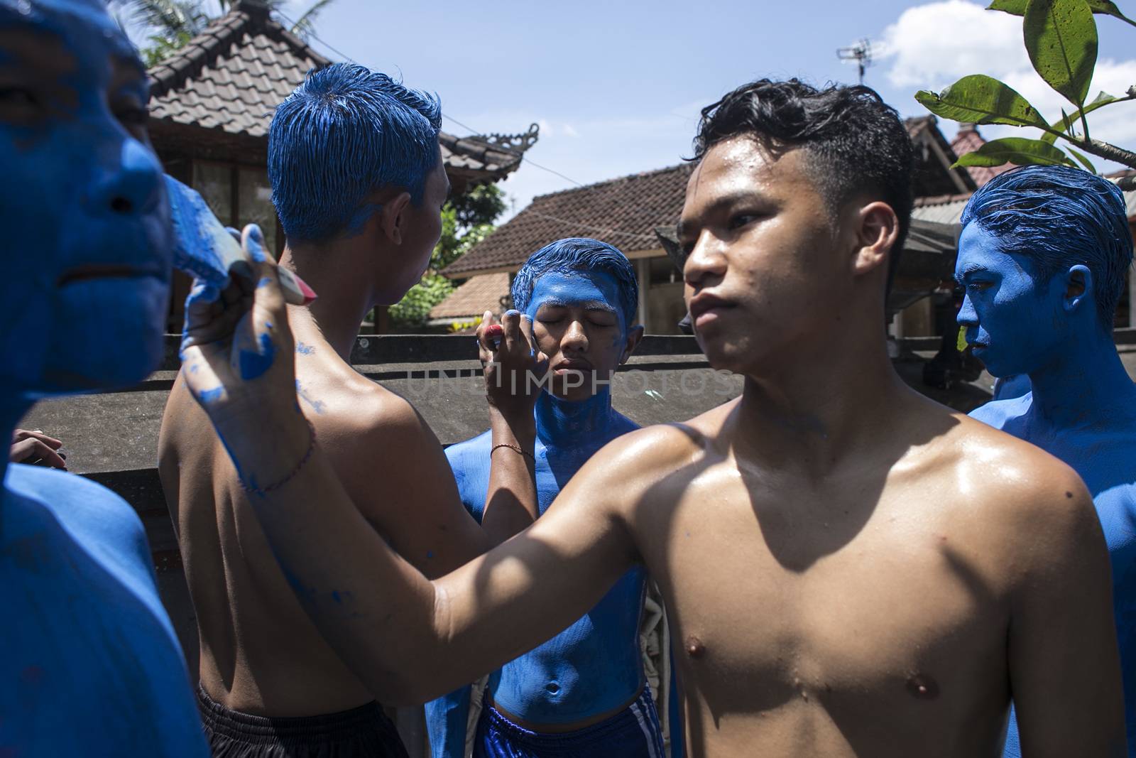 INDONESIA, Gianyar, Bali: A Balinese teenager paints the body of one of his friends, during the Grebeg ritual, on March 16, 2016, in Tegallalang village, Gianyar, Bali, Indonesia. During the biannual ritual, young members of the community parade through t