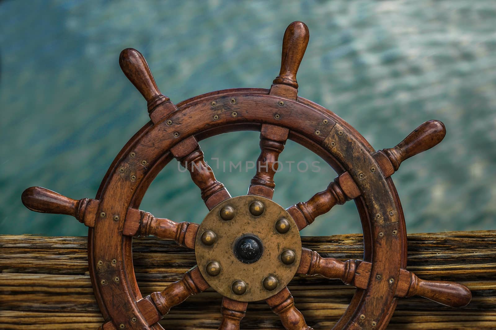 Nautical Detail Of A Ship's Wheel Against Tropical Ocean Water