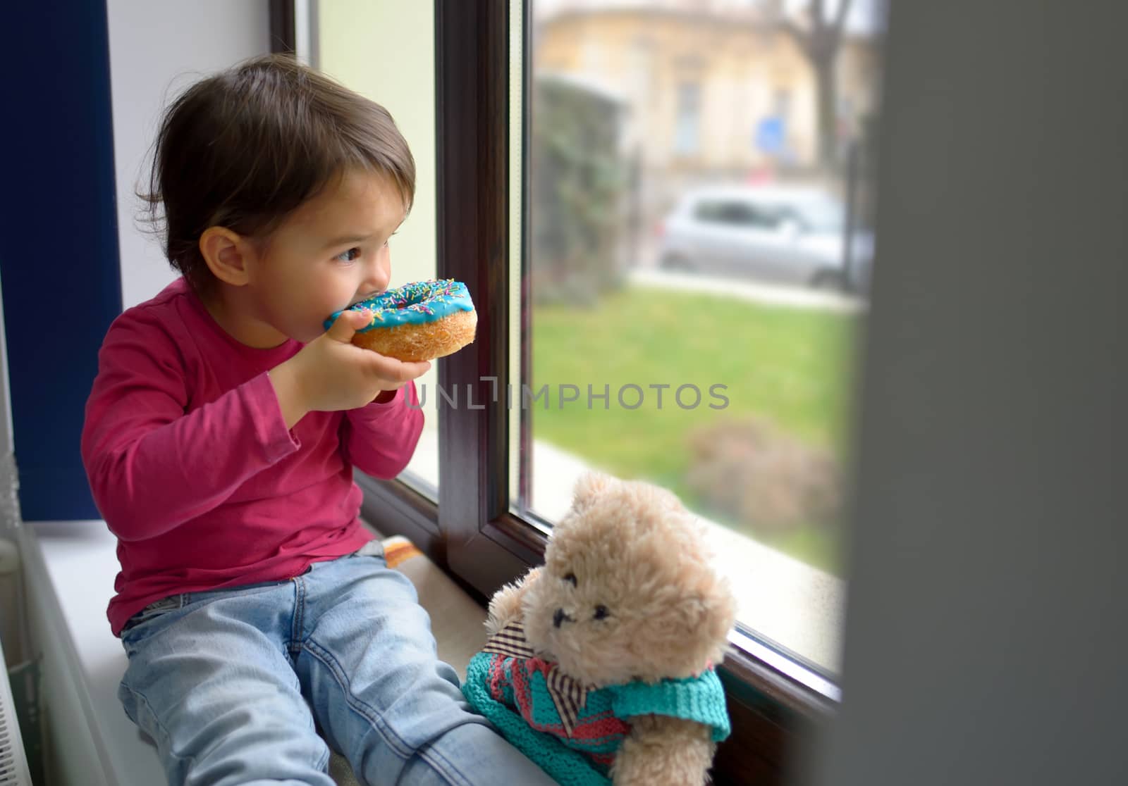 little girl and her bear toy eating  donuts