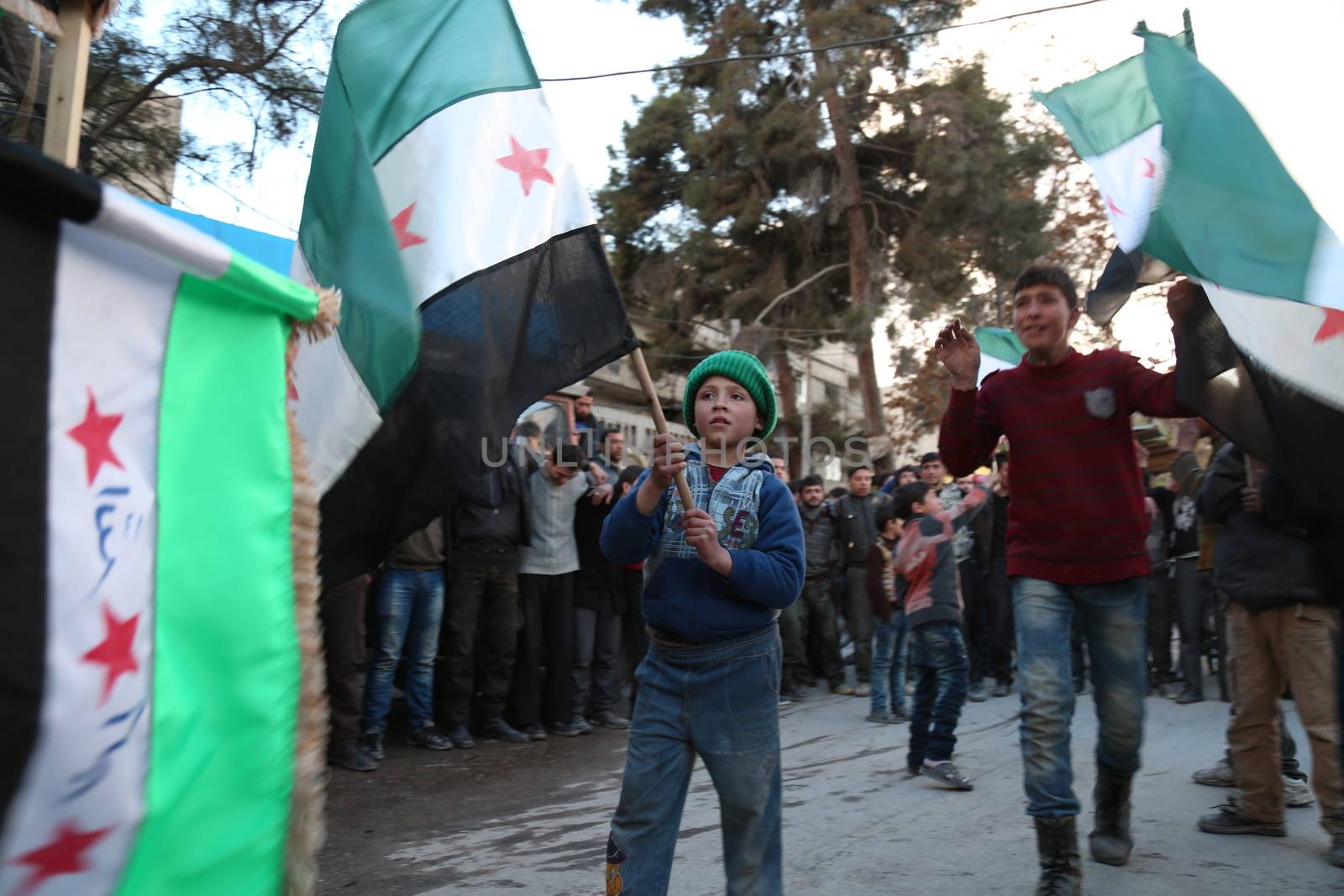 SYRIA, Saqba: A child holds a pre-Baath Syrian flag, that was adopted by the Syrian revolution during the uprising, on March 16, 2016 in Saqba, near Damascus, southern Syria, during a protest to mark the fifth anniversary of Syria's revolution. The conflict began with anti-regime protests in mid-March 2011 and spiralled into a bloody war after a harsh government crackdown on demonstrators. 