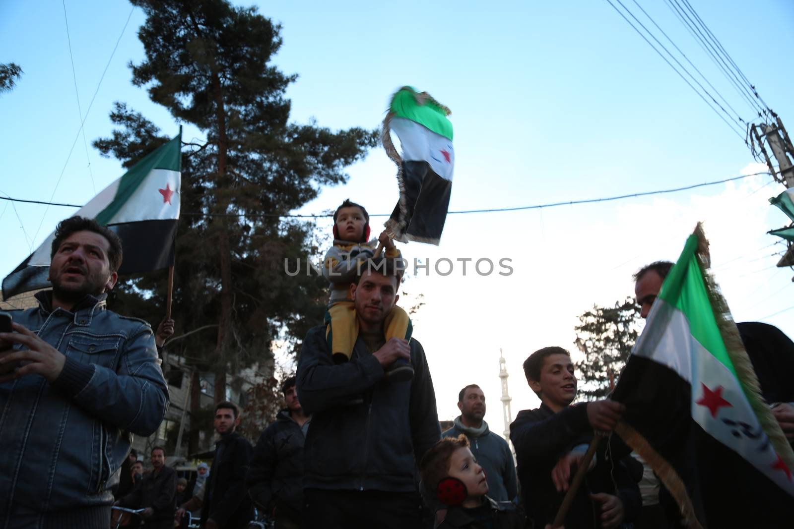 SYRIA, Saqba: A child holds a pre-Baath Syrian flag, that was adopted by the Syrian revolution during the uprising, on March 16, 2016 in Saqba, near Damascus, southern Syria, during a protest to mark the fifth anniversary of Syria's revolution. The conflict began with anti-regime protests in mid-March 2011 and spiralled into a bloody war after a harsh government crackdown on demonstrators. 