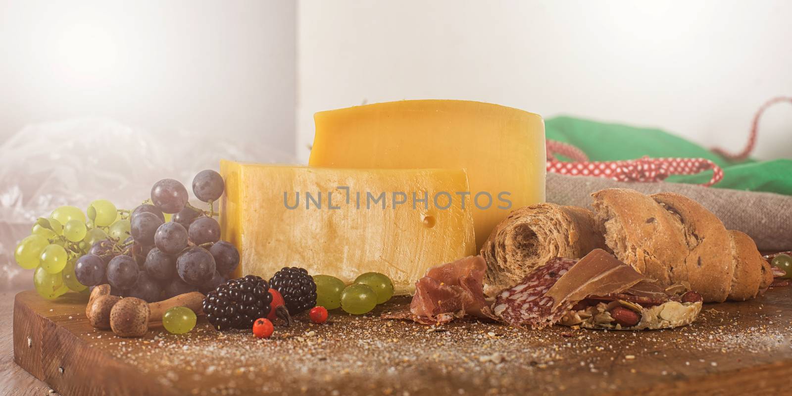 Fresh grapes, cheese bacon berries and salami on wooden table