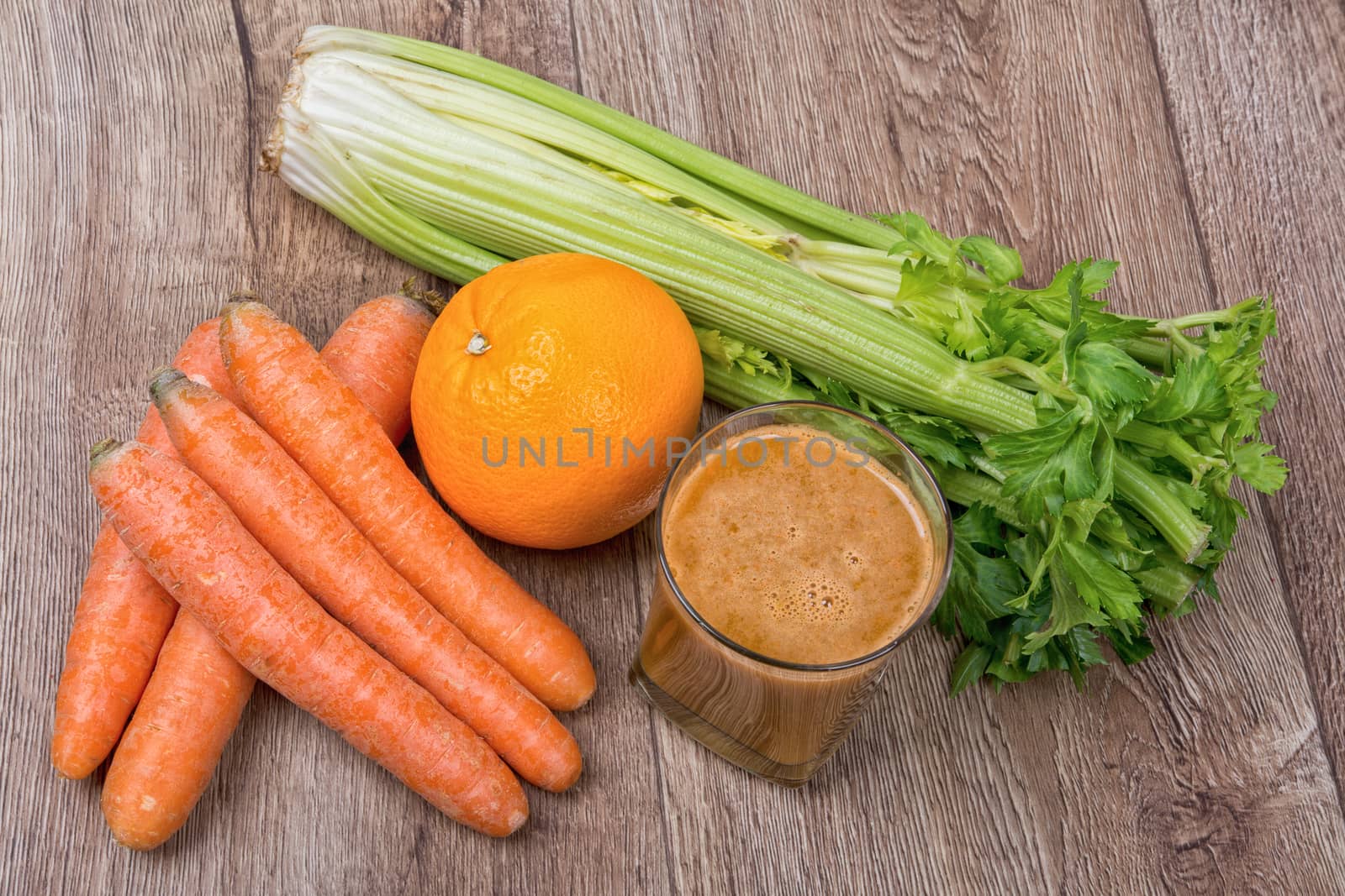 Blended dark orange smoothie with ingredients on wooden table