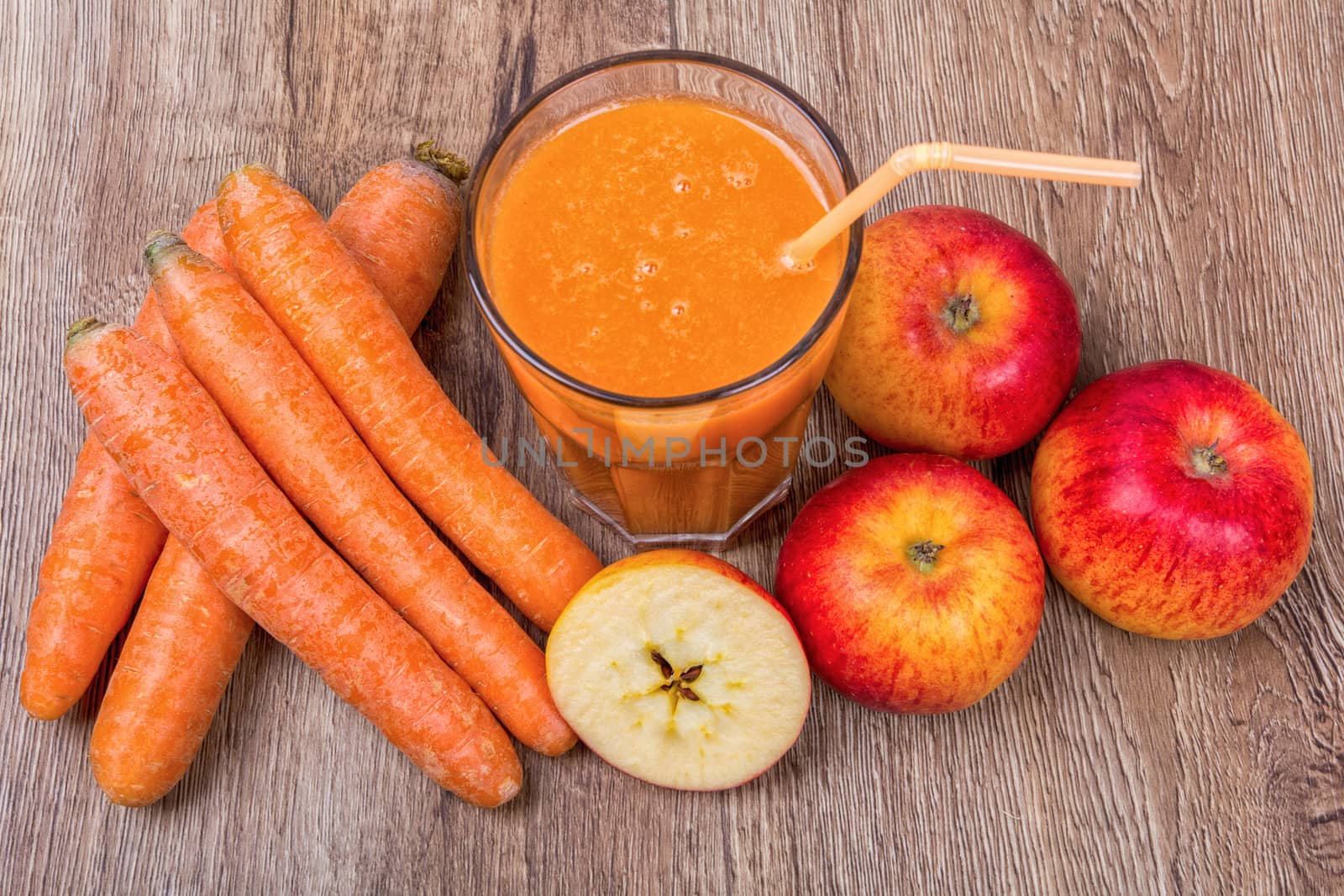 Blended light orange smoothie with ingredients on wooden table