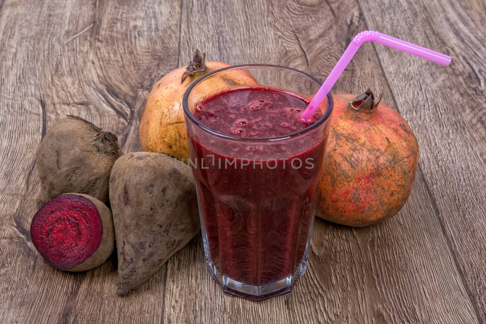 Blended dark red smoothie with ingredients on wooden table