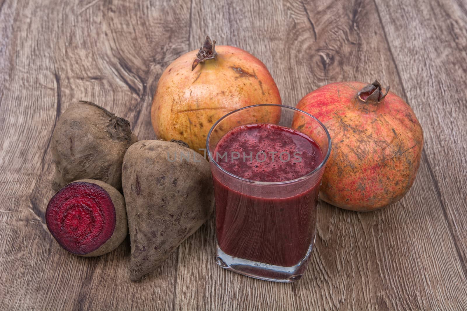 Blended dark red smoothie with ingredients on wooden table