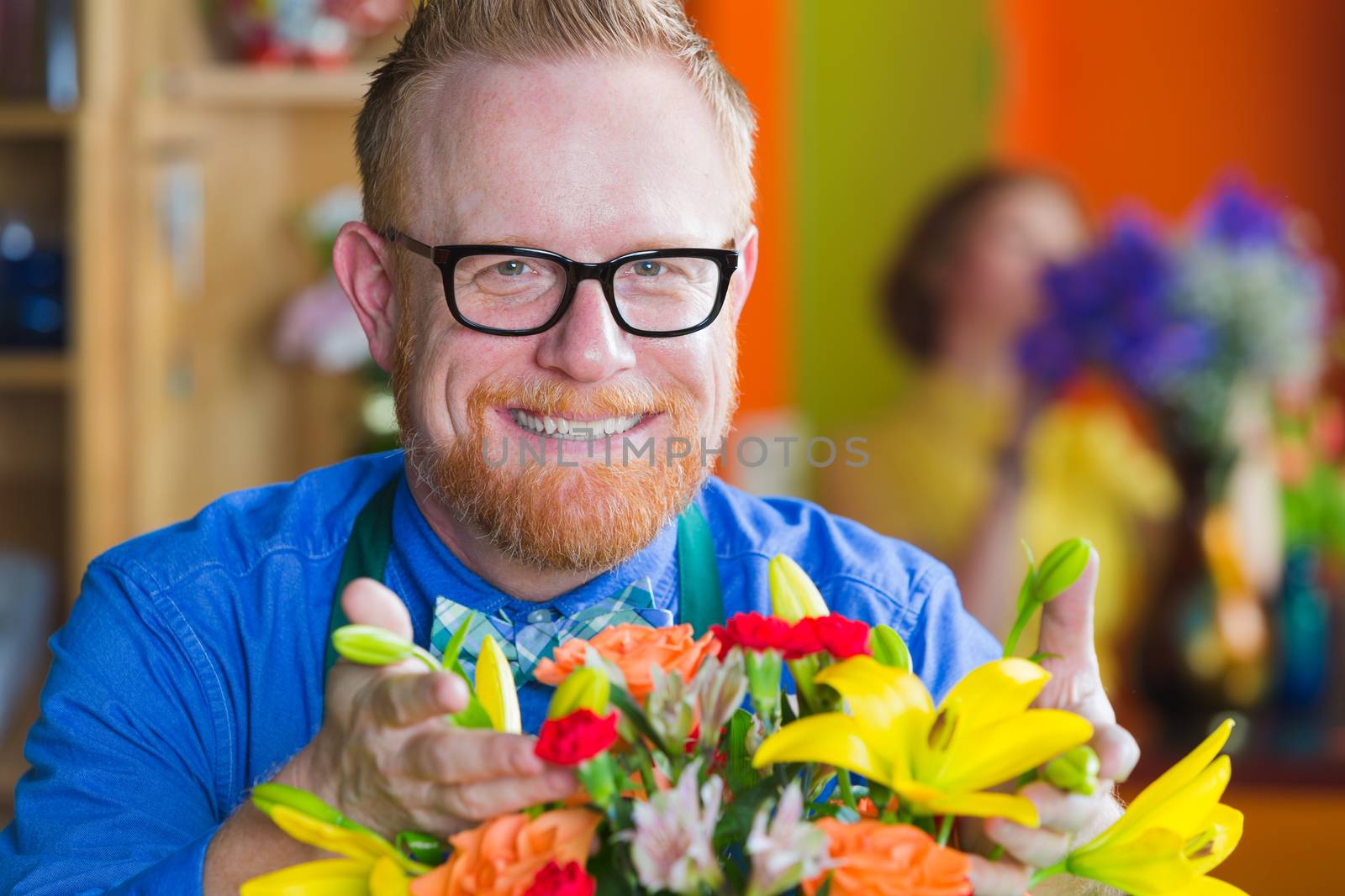 Smiling male owner with arrangement in a busy flower shop