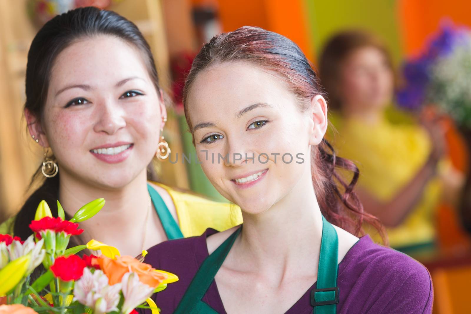 Two beautiful young female employees in a busy flower shop