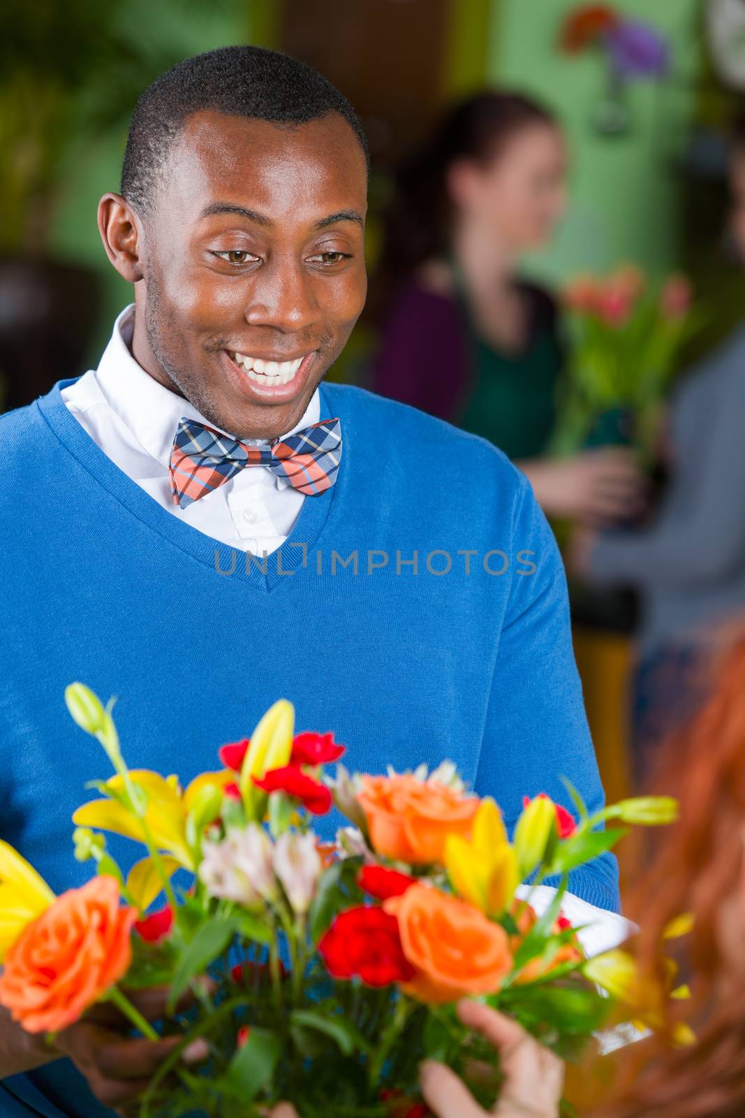 Handsome happy single African American male customer in a busy flower shop