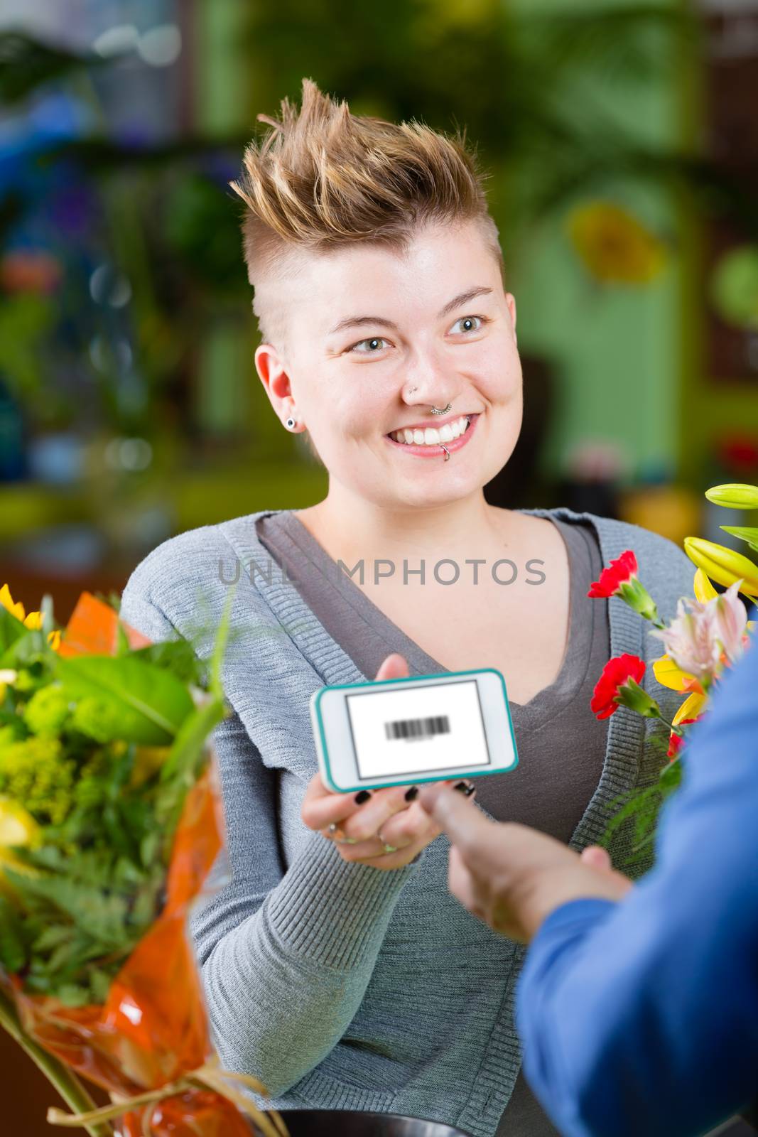 Cute female customer in store showing clerk phone with electronic coupon displayed