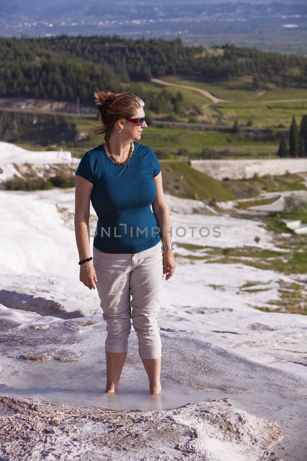 Pretty woman tourist wading in hot springs pool at Pamukkale