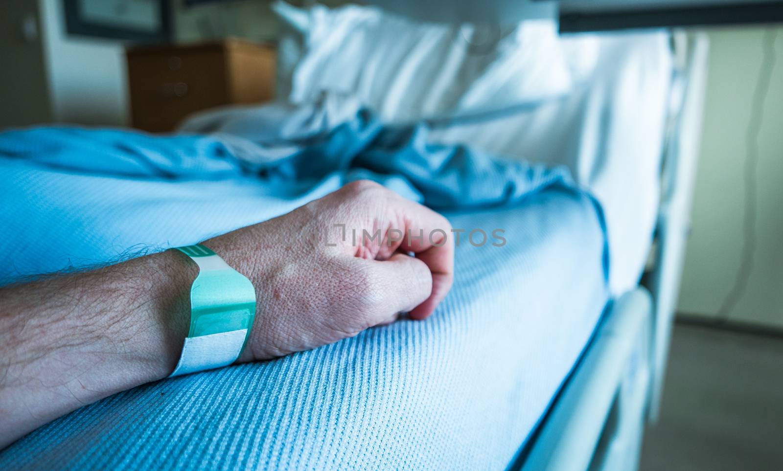Detail Of A Man's Arm On A Hospital Bed With Wrist Tag