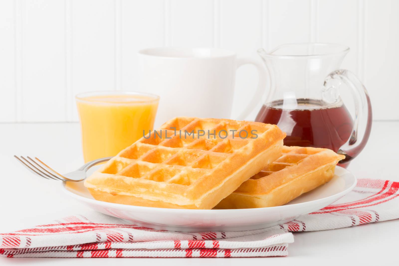 Fresh made waffles with maple syrup, coffee and juice.