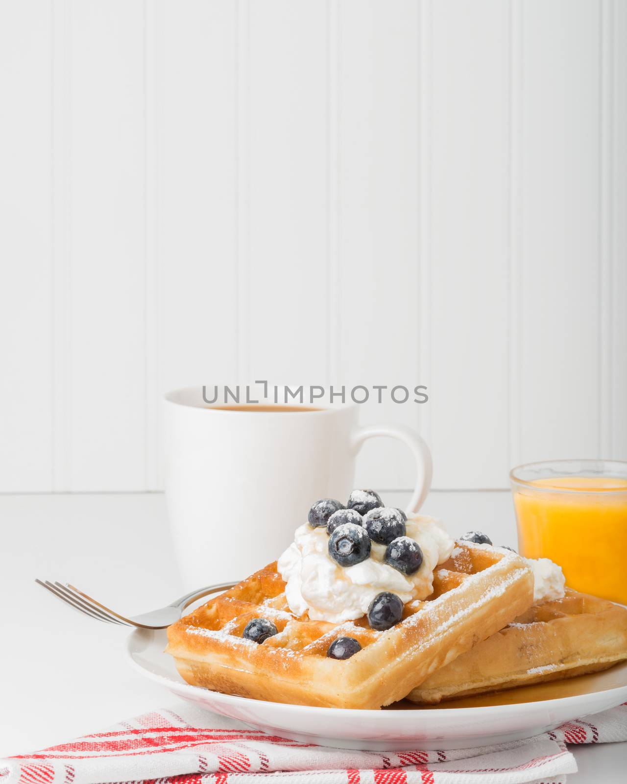 Plate of waffles and blueberries with whipped cream.