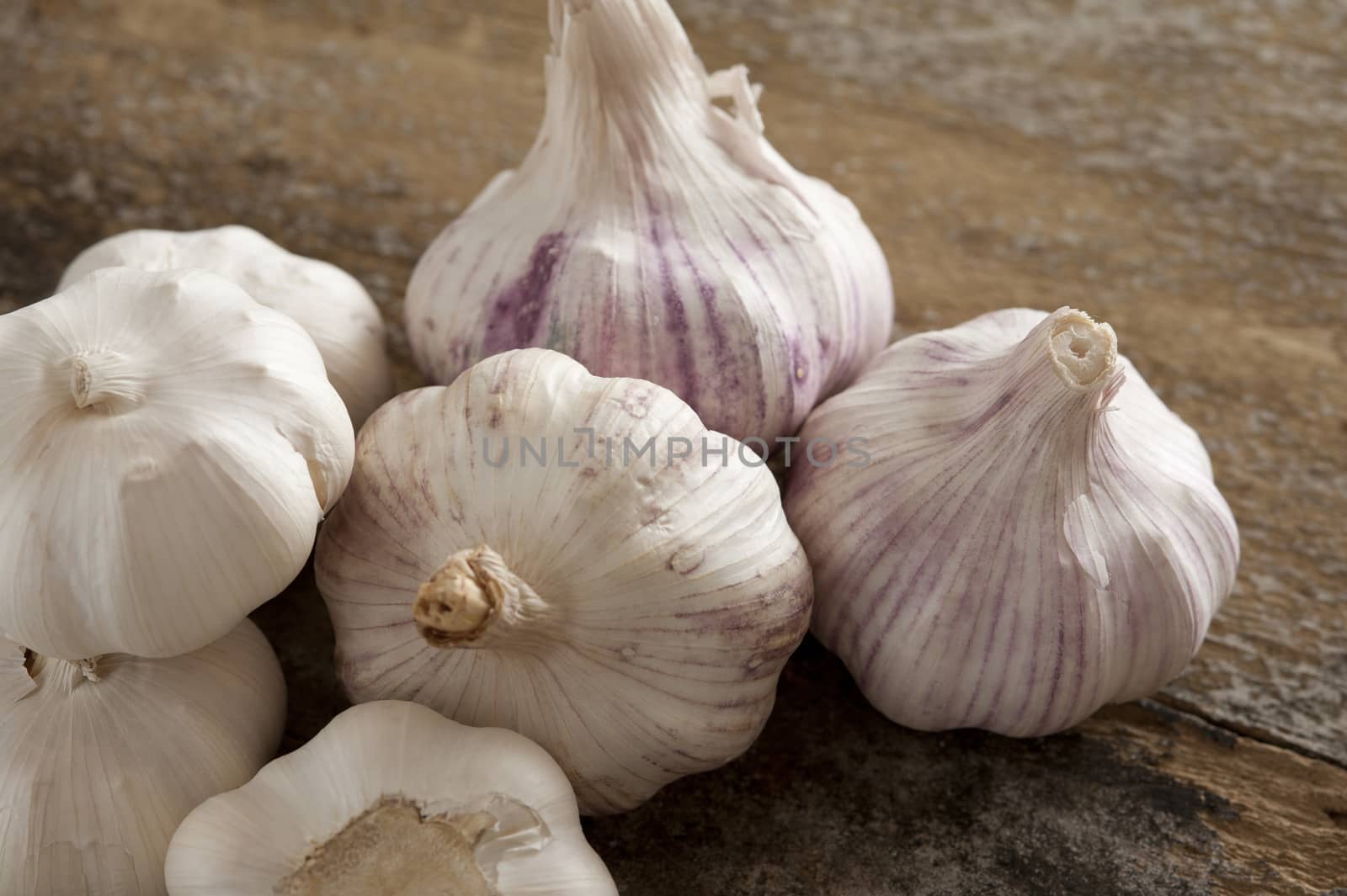 Group of fresh garlic bulbs for use as a pungent aromatic seasoning in cookery lying on a wooden table