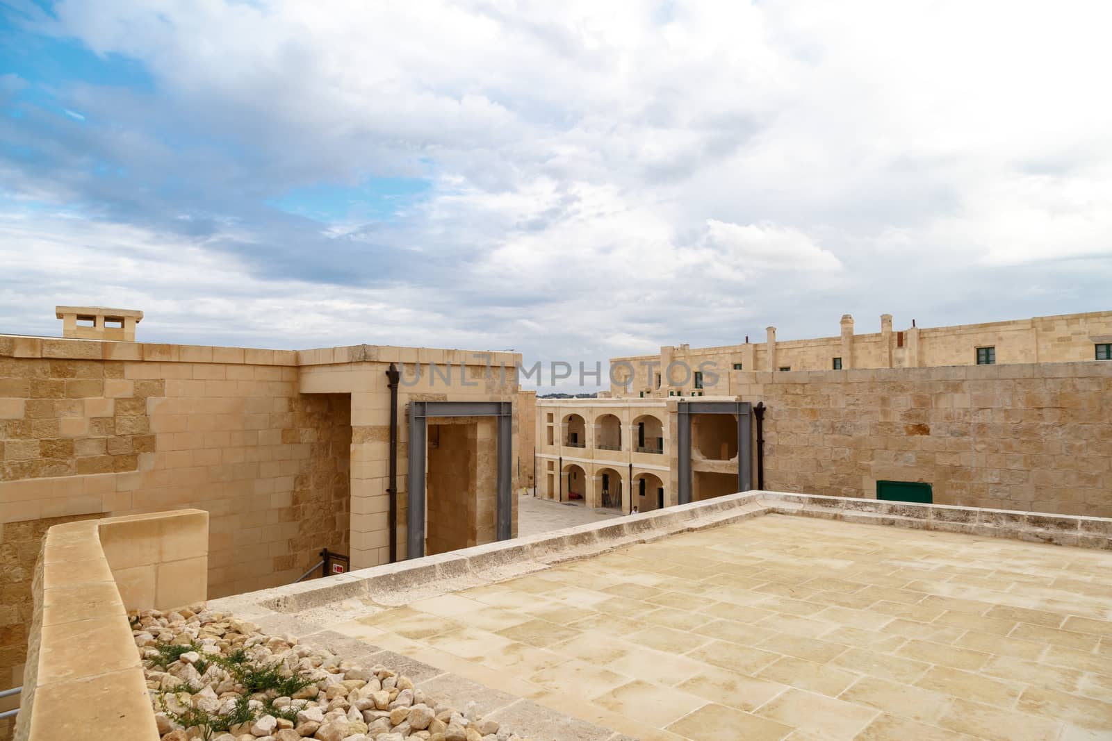 View of National War Museum in Valletta, Malta with high yellow stone walls, on cloudy sky background.