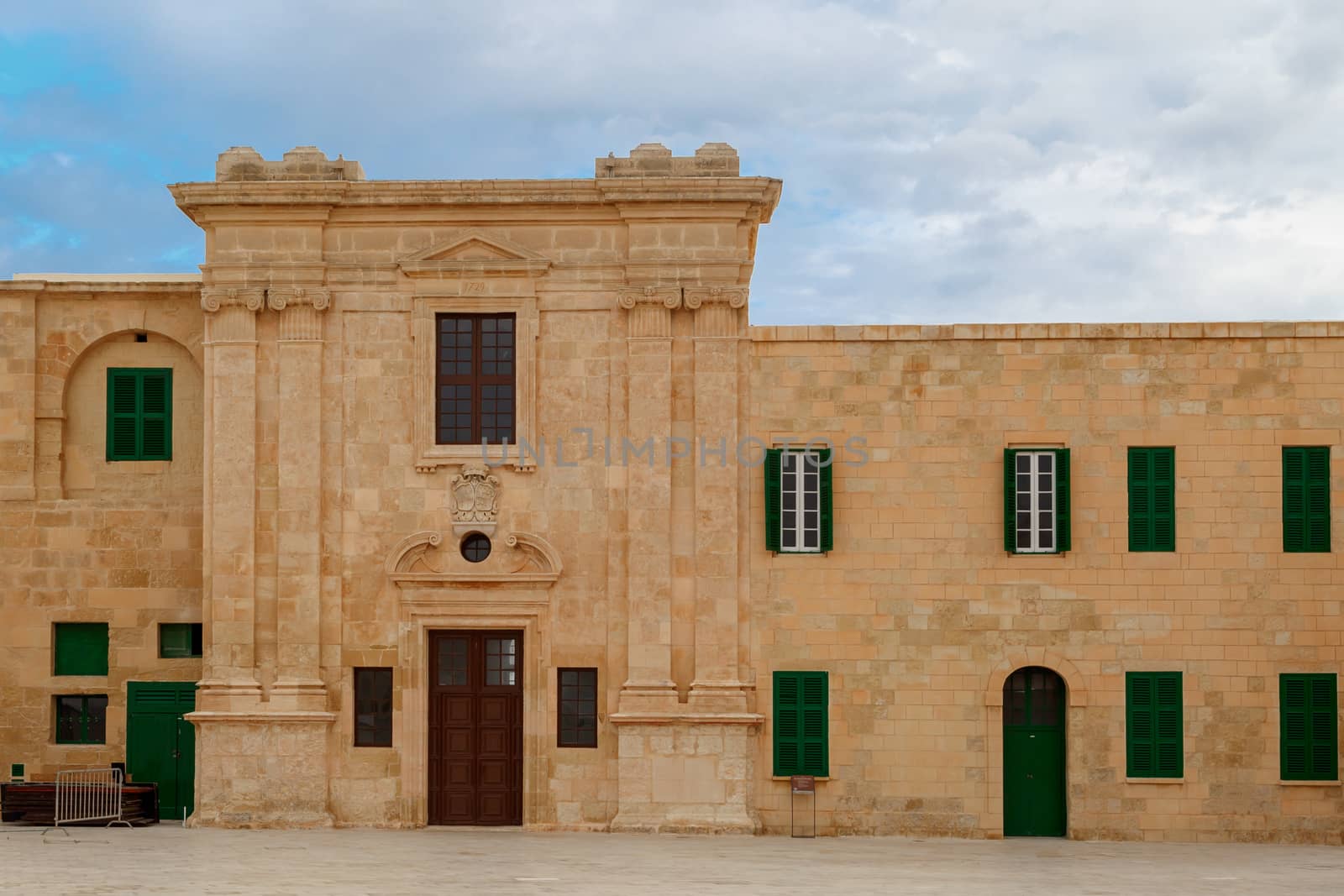 View of National War Museum in Valletta, Malta with high yellow stone walls, on cloudy sky background.