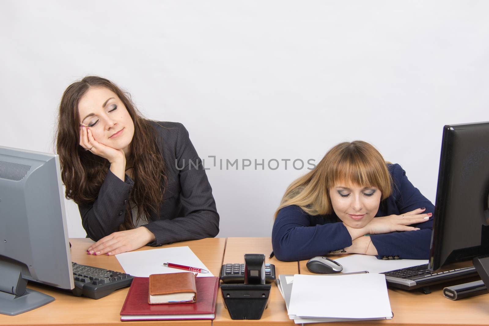 Two young office employee asleep on desk for computers