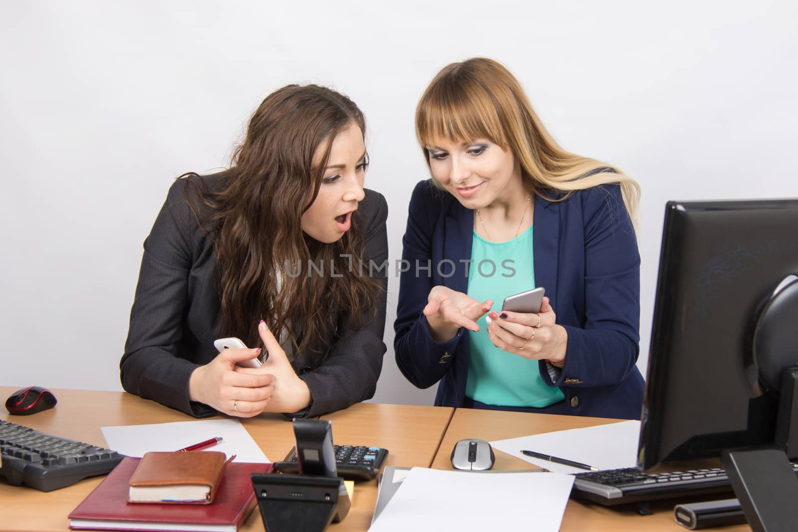 Office workers animatedly discussing personal issues and looking at mobile phone by Madhourse