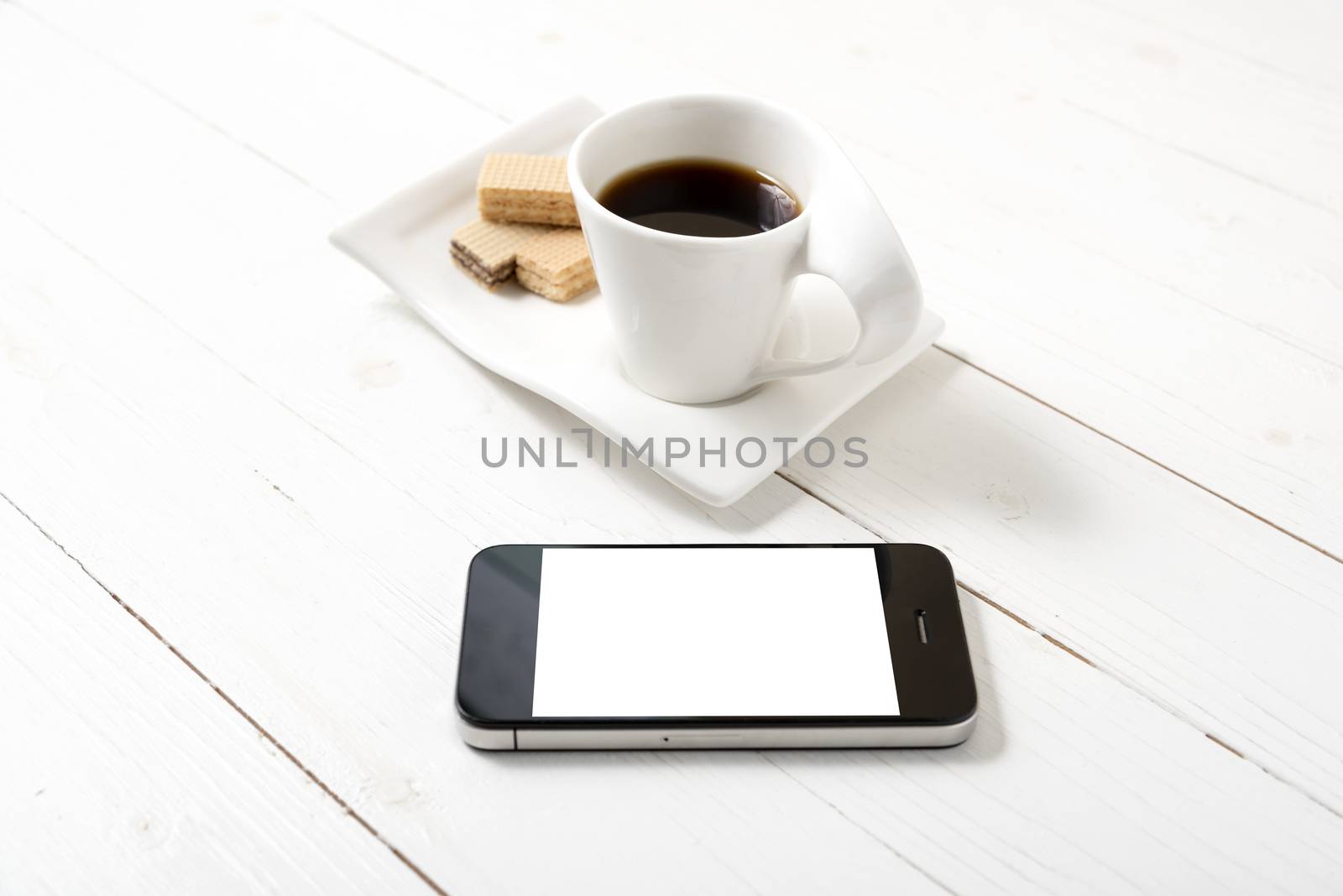 coffee cup with wafer and phone on white wood background