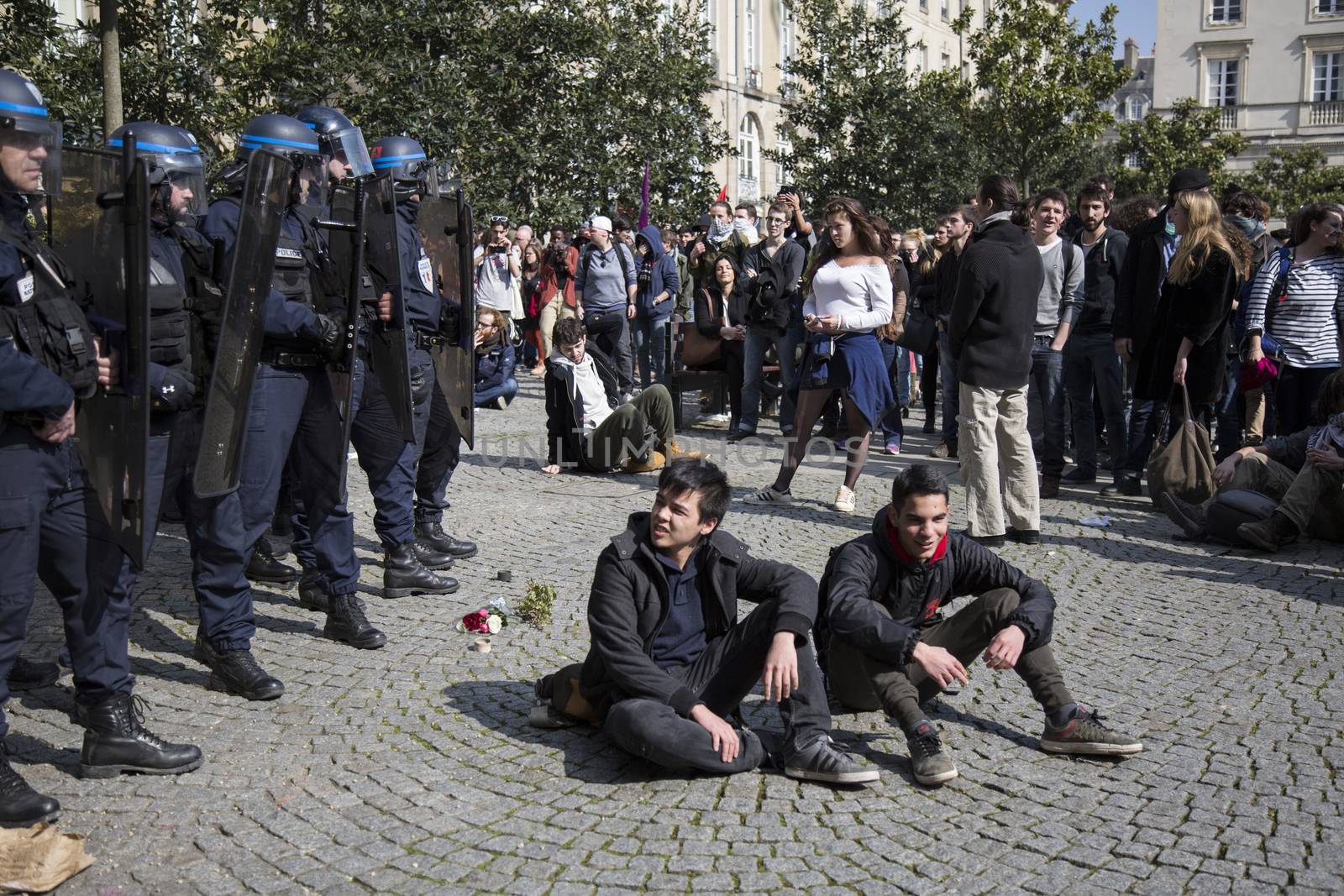 FRANCE, Paris: Two young men sit on a square next to policemen as high school students and youths demonstrate in front of Rennes' town hall, western France,  during a protest march opposing the government's labour reforms on March 17, 2016. The contested reform is designed to inject more flexibility into the labour market by dropping key measures that would have benefited smaller companies. In a significant change from the original text, French Prime minister said on Monday that small and medium-sized companies would not be able to unilaterally introduce flexible work practices into their working week.