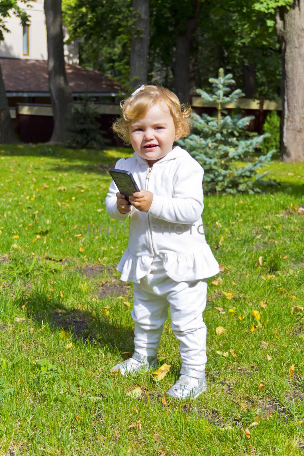 Caucasian beautiful cute infant girl in summer with mobile phone