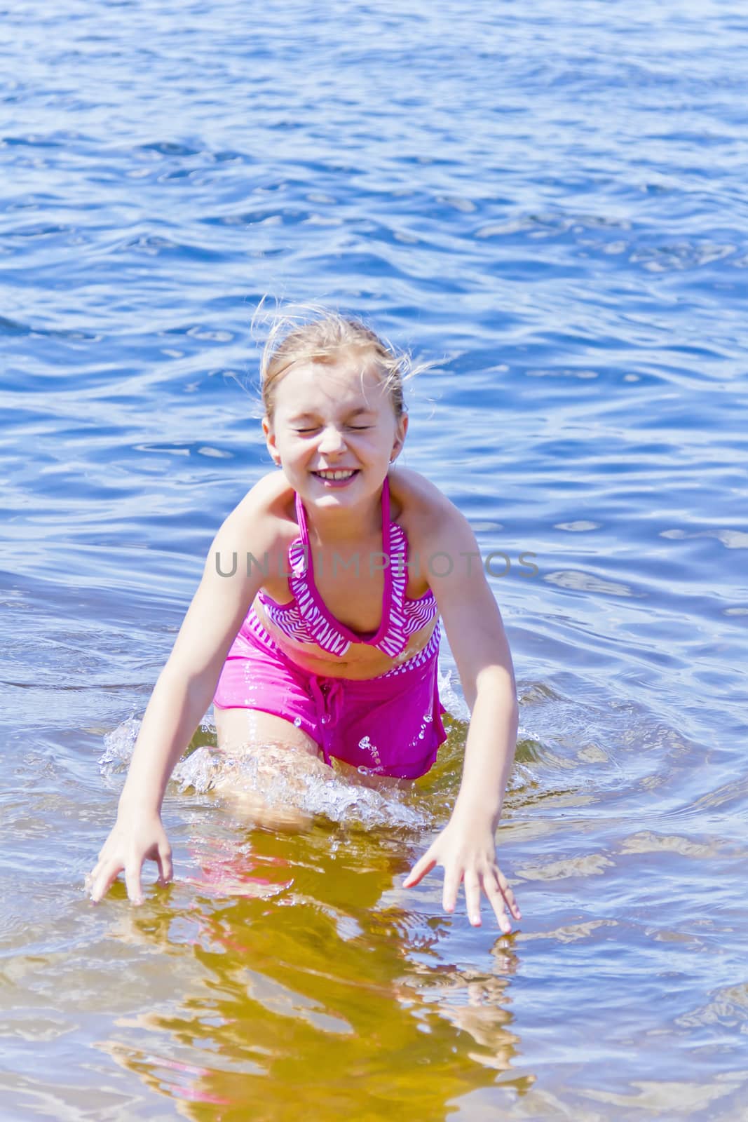 Jumping girl in pink swimsuit with droplets of water