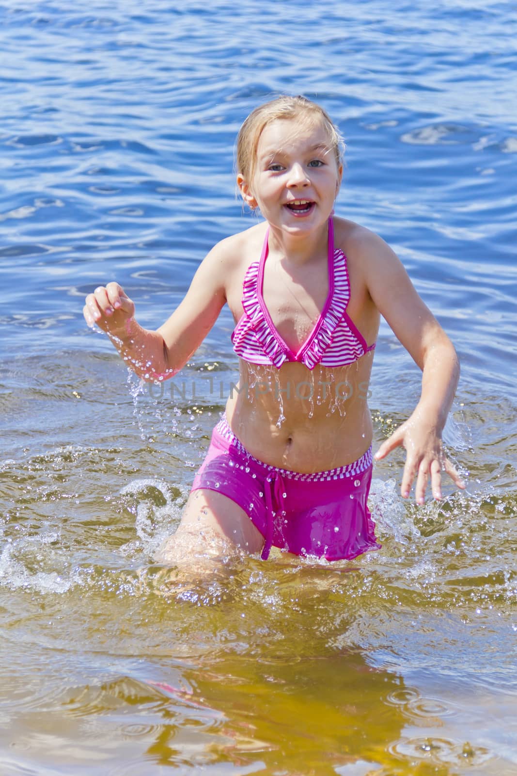 Jumping girl in pink swimsuit with droplets of water