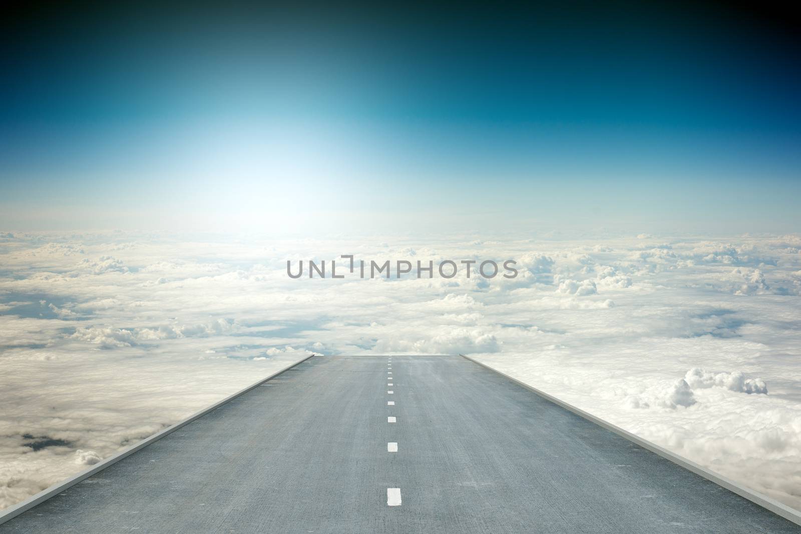 Road over clouds in blue sky and sun