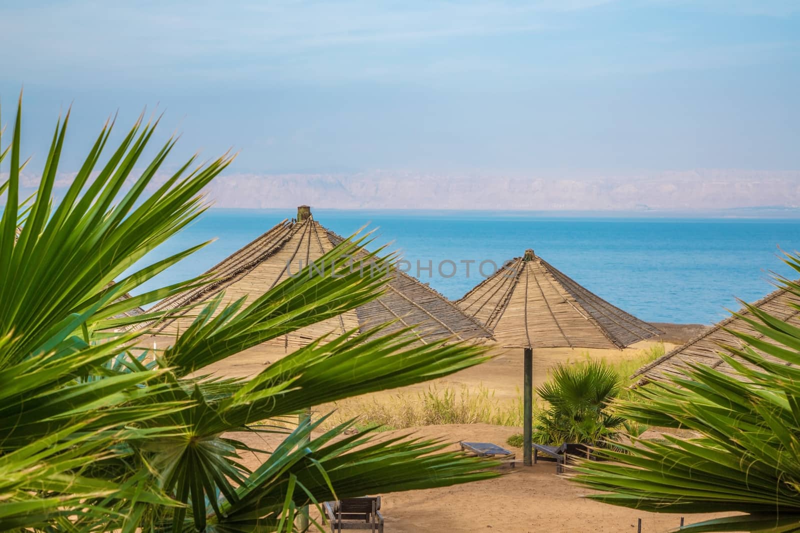 A nice sunny day at the Dead Sea resort. Blue beach chairs and umbrellas waiting for tourists.