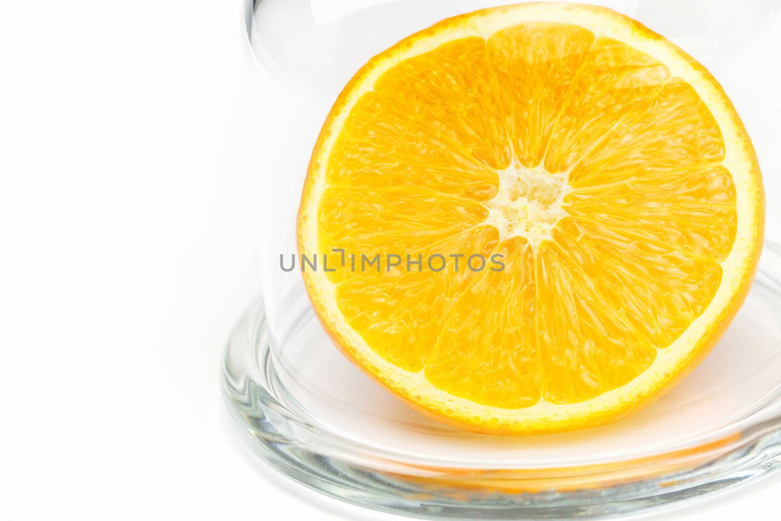 Slice a fresh juicy  round orange in a transparent glass bowl isolated on white 